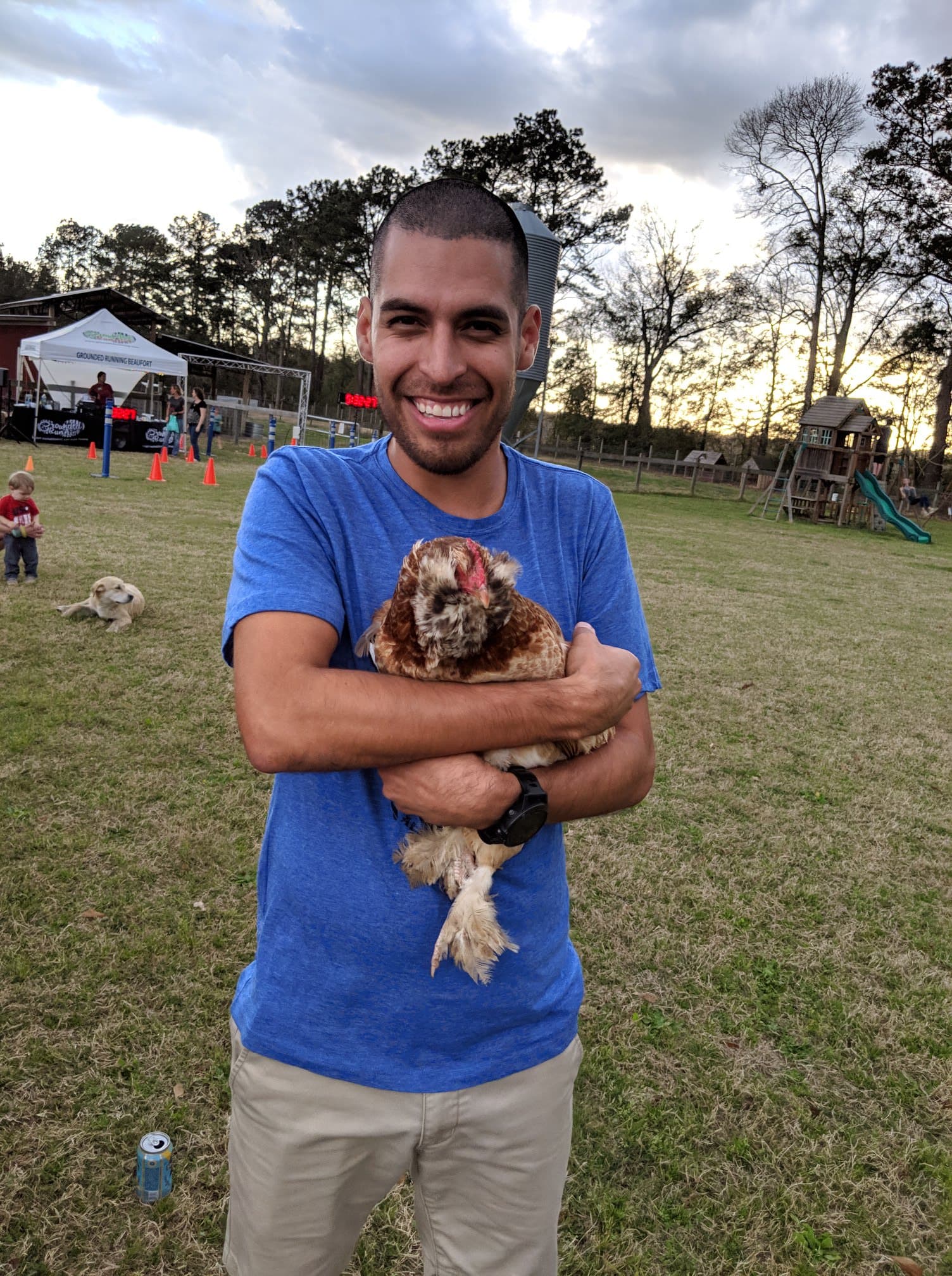 Man smiling while holding a chicken on the farm