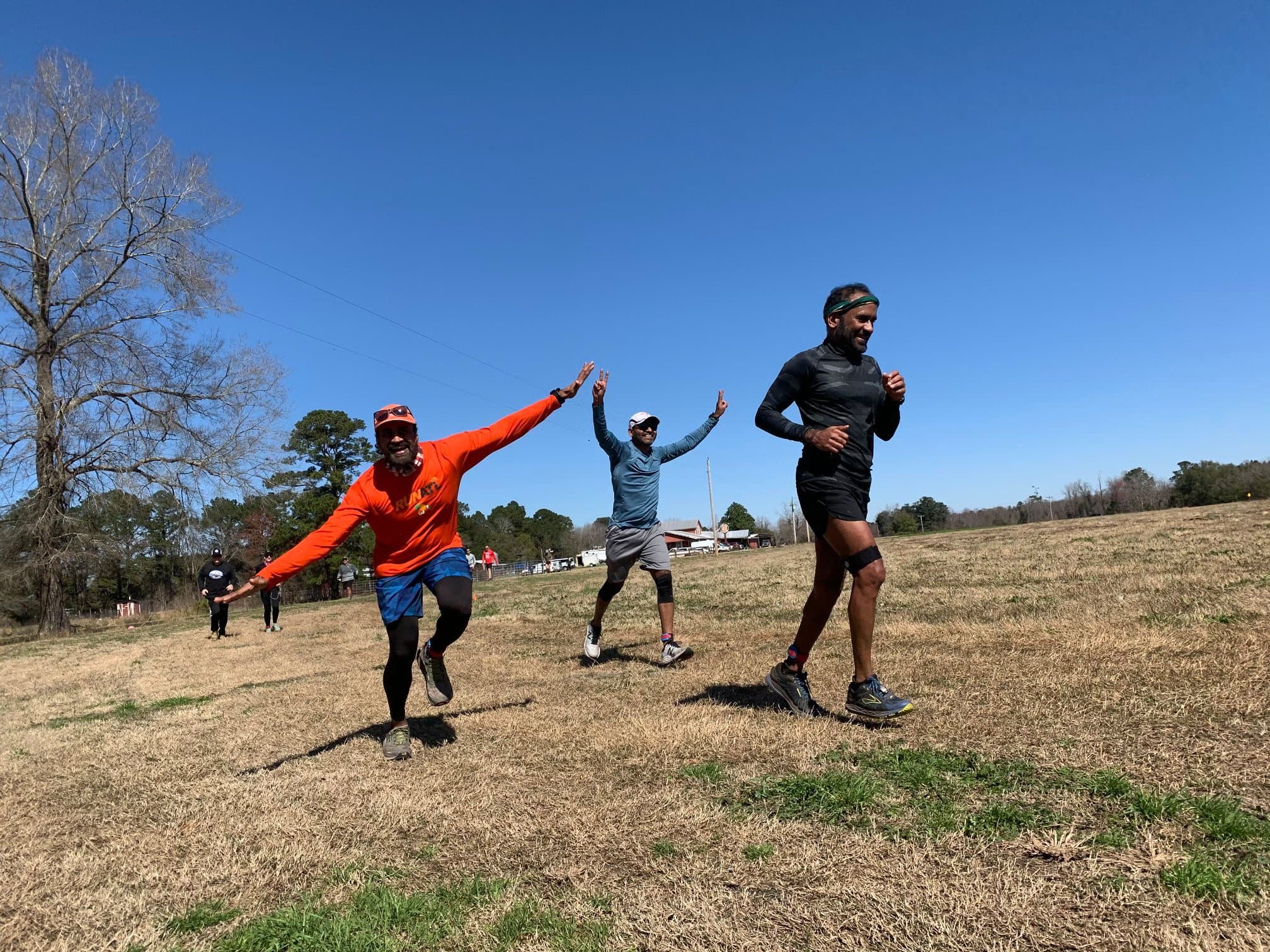 Runners laughing with arms wide open in the field